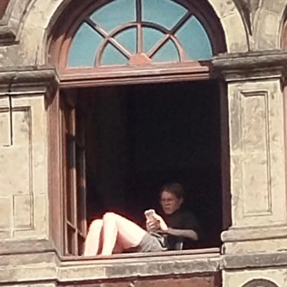 Mujer toma el sol desde ventana de Palacio Nacional