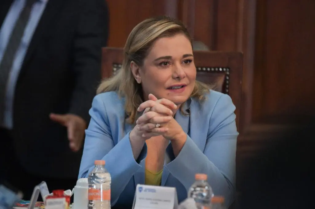 Woman in blue blazer clasping hands at meeting
