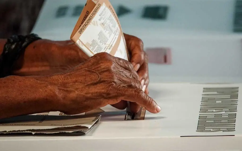 Hands inserting ballot into voting box