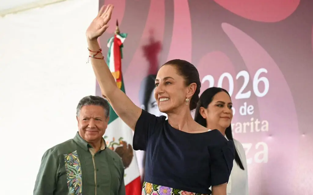 Smiling woman waving in front of Mexican flag