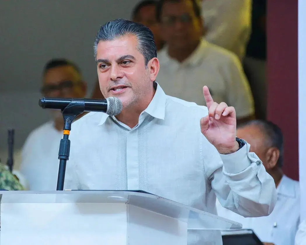 Man speaking at podium, raising finger