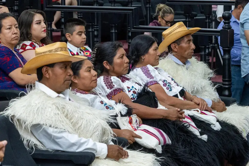 Indigenous community members in traditional garments seated