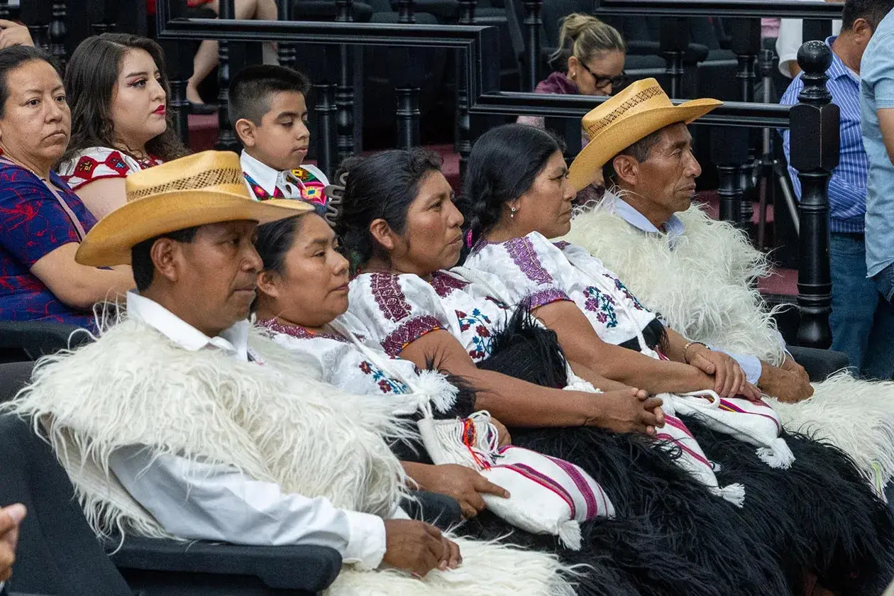 Indigenous community members in traditional garments seated