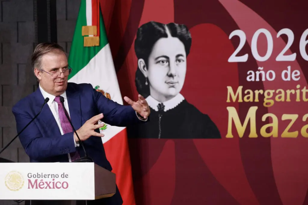 Official at podium with Mexican flag and portrait