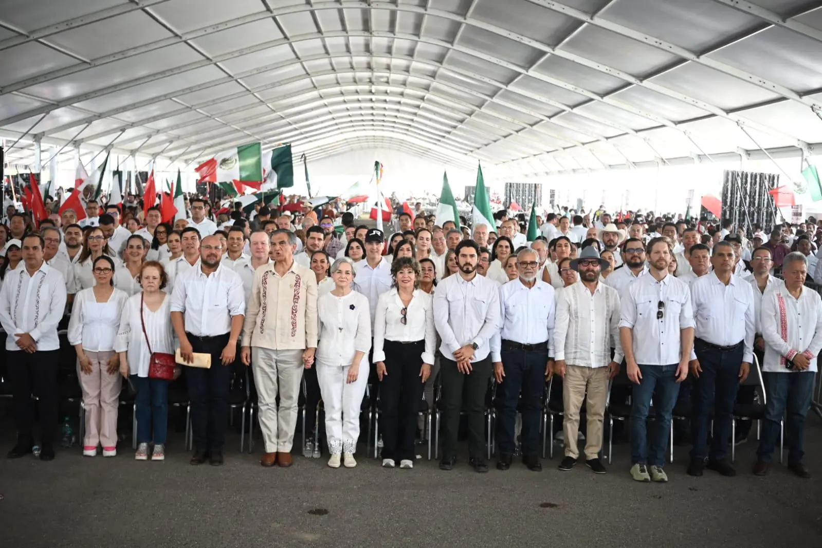 Large crowd of people standing under tent