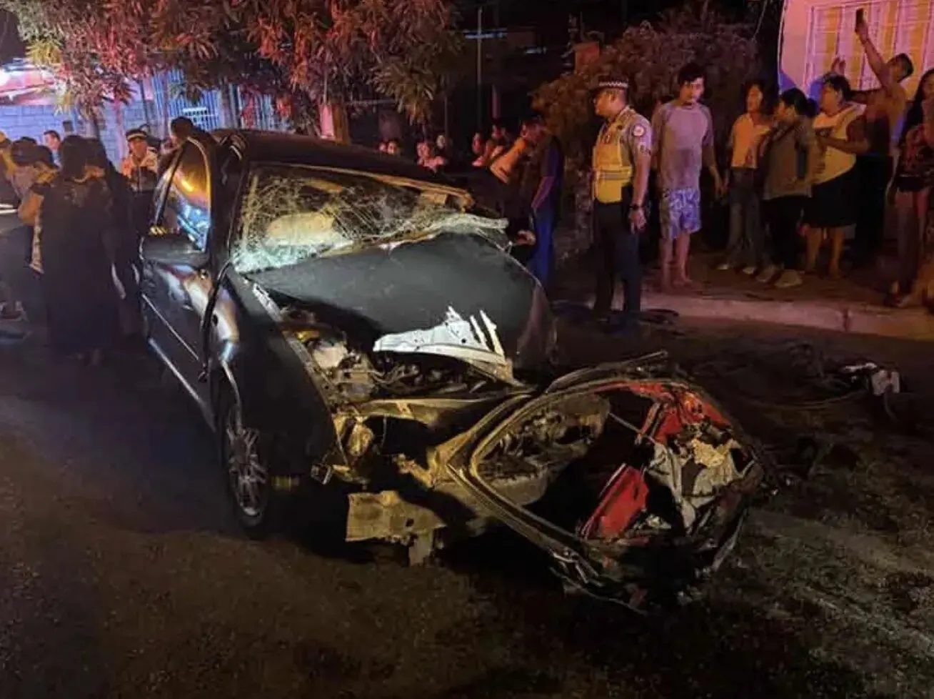 Heavily damaged car crash scene at night