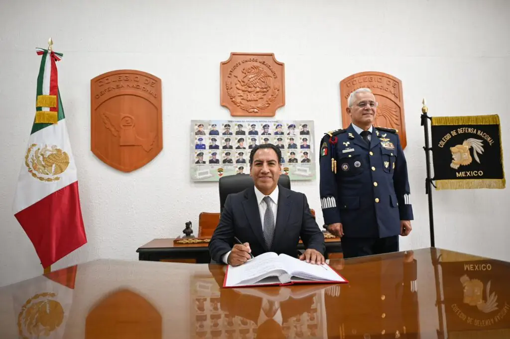 Mexican official signing document beside uniformed officer