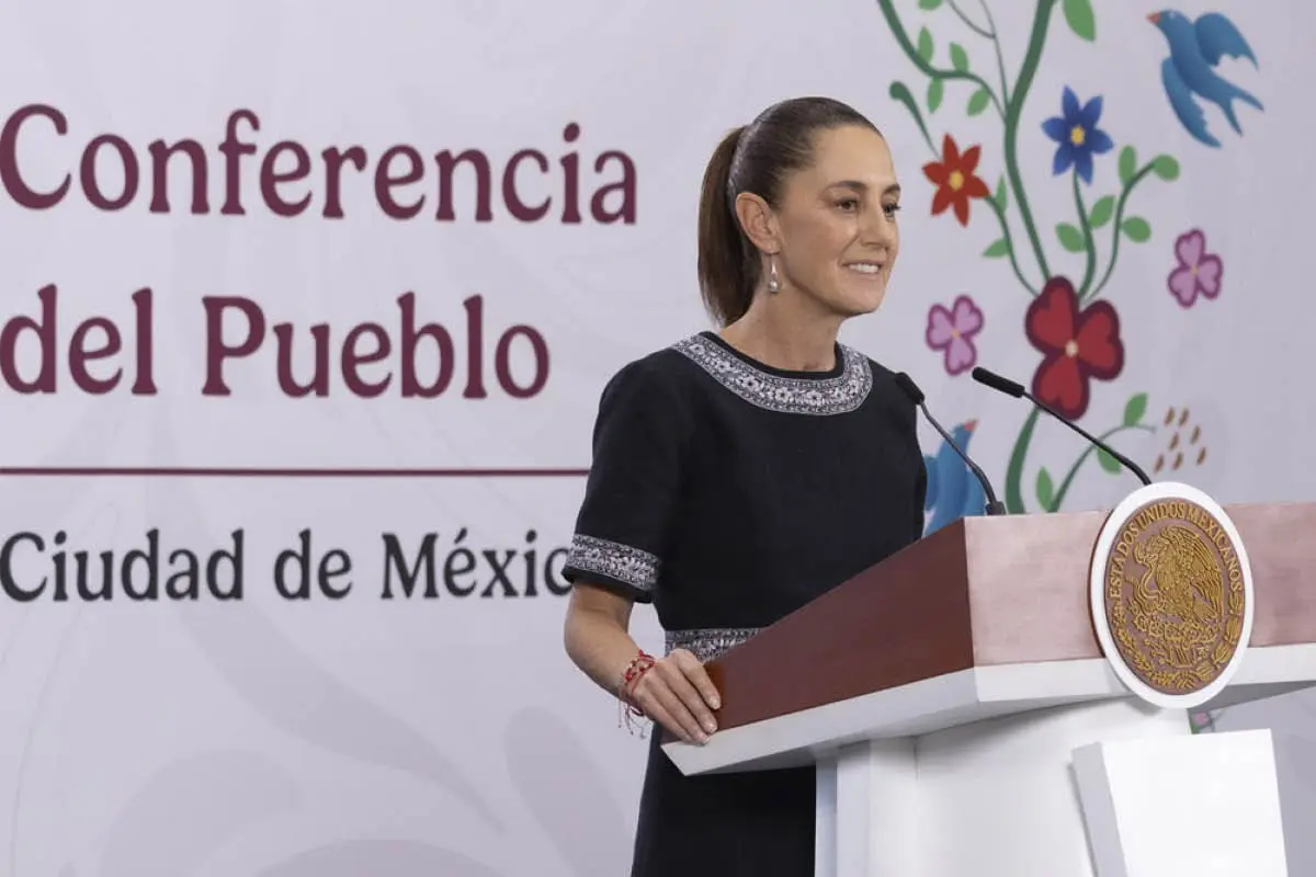 Woman speaking from podium wearing black embroidered dress