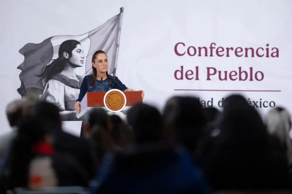 Speaker addressing seated audience with mural backdrop