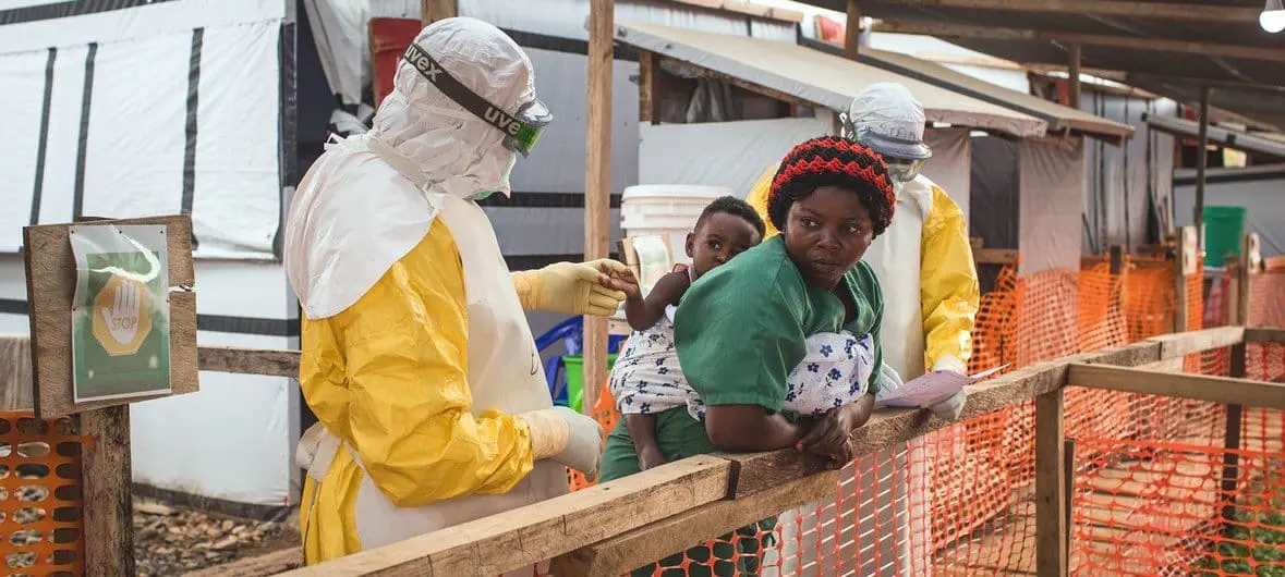 Health worker in PPE with mother and child
