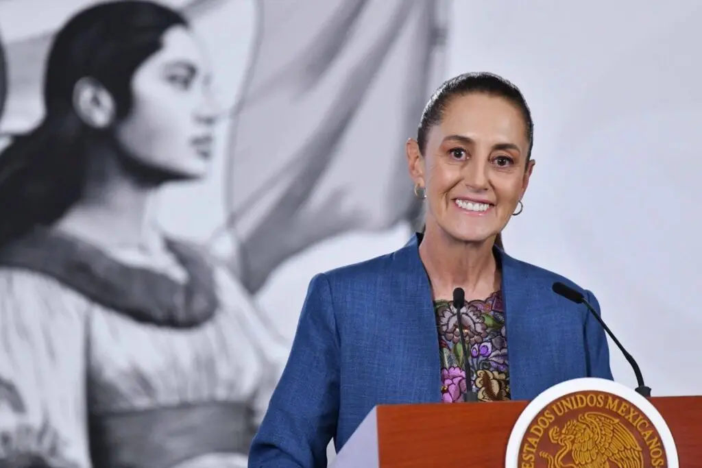 Smiling woman speaking at podium, mural behind