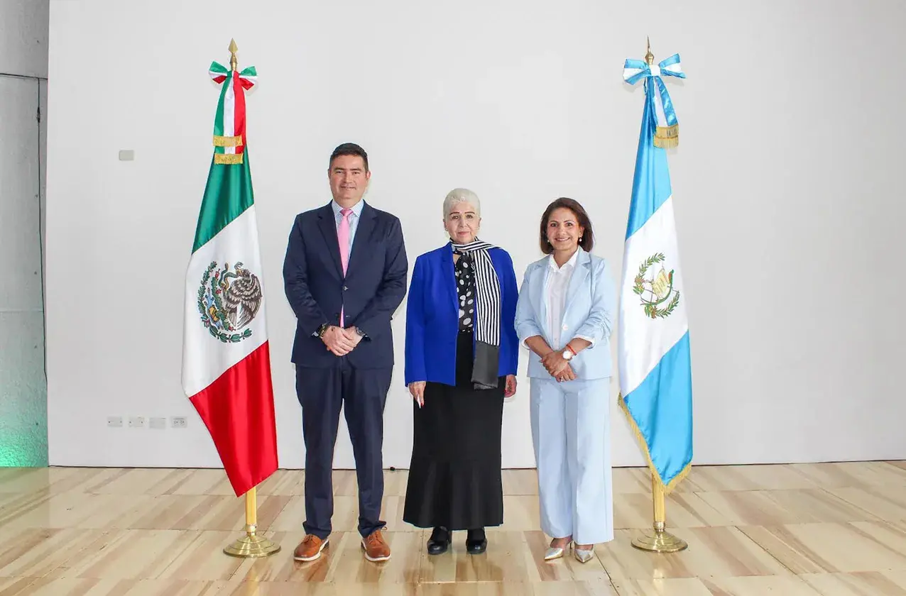 Three officials standing between Mexican and Guatemalan flags