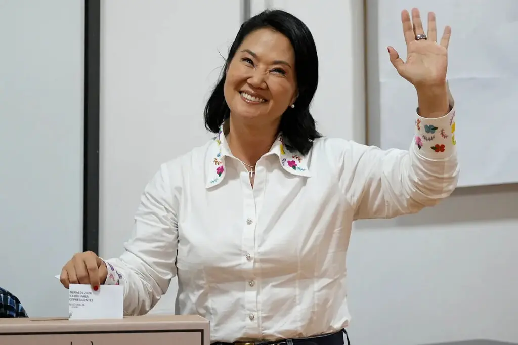 Smiling woman waving while casting a ballot