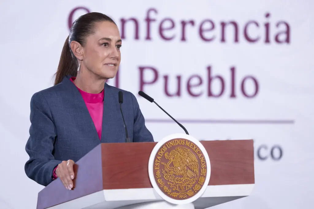 Woman giving speech at podium with Mexican seal