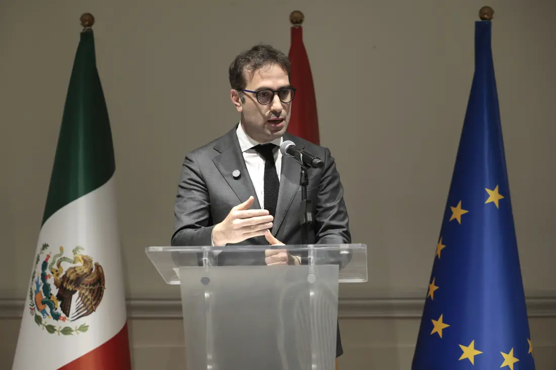 Speaker at podium between Mexican and EU flags