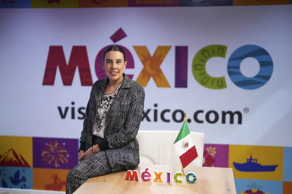 Woman by Mexico tourism sign and flag