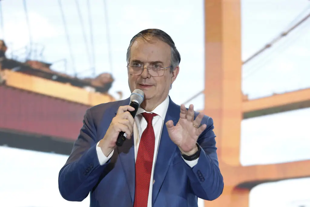 Speaker wearing glasses and blue jacket with mic