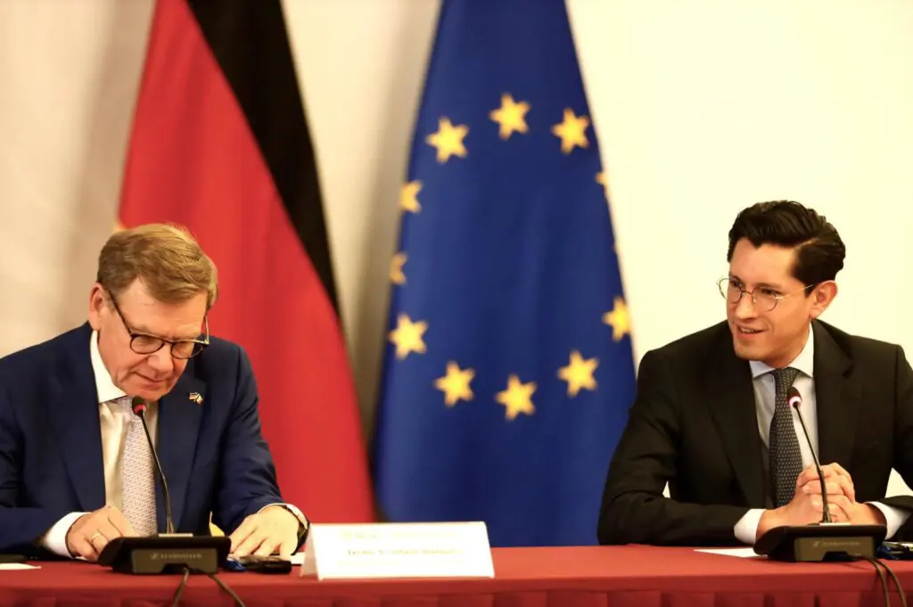Two delegates seated, German and EU flags