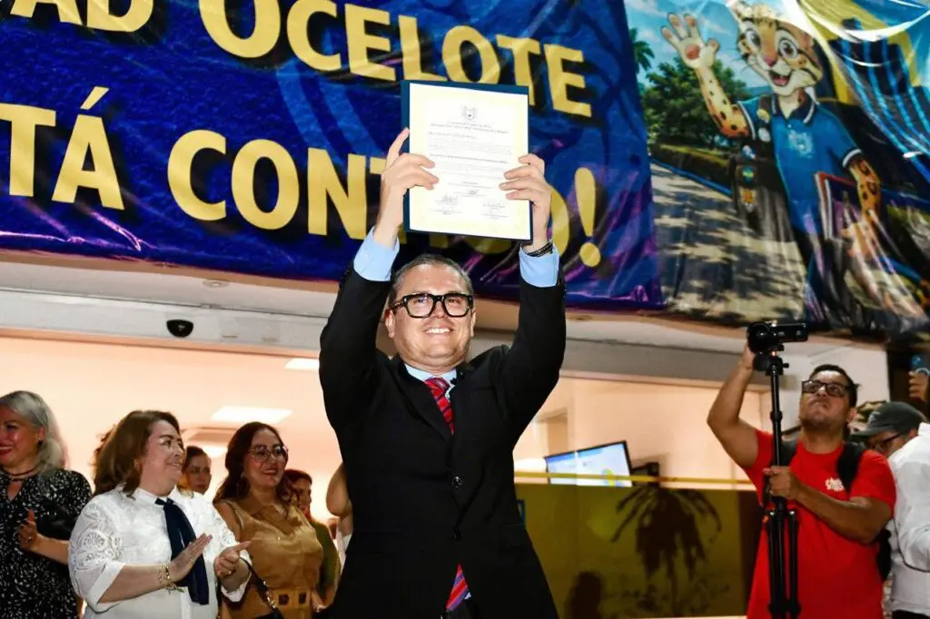 Person holding certificate aloft amid applauding crowd