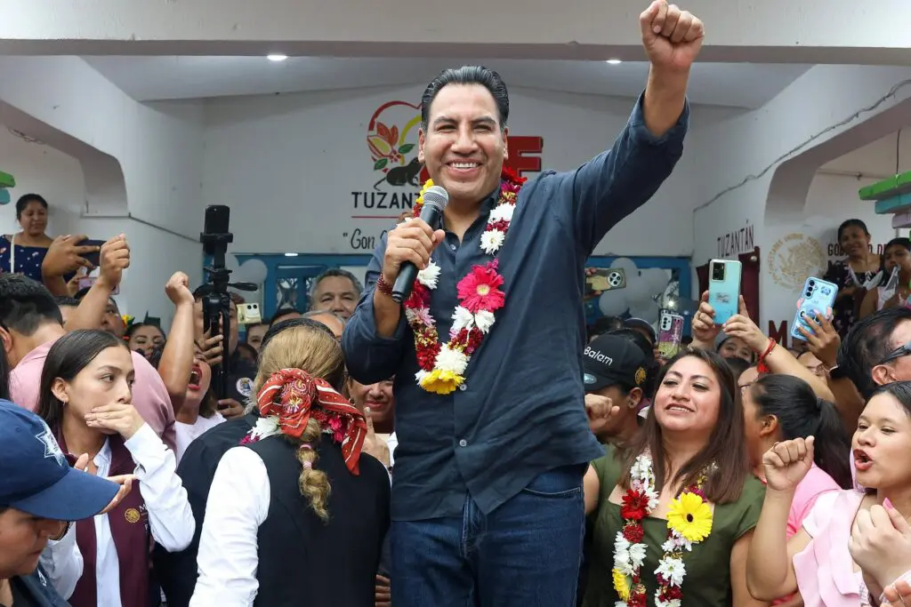 Man speaking at campaign rally with cheering crowd