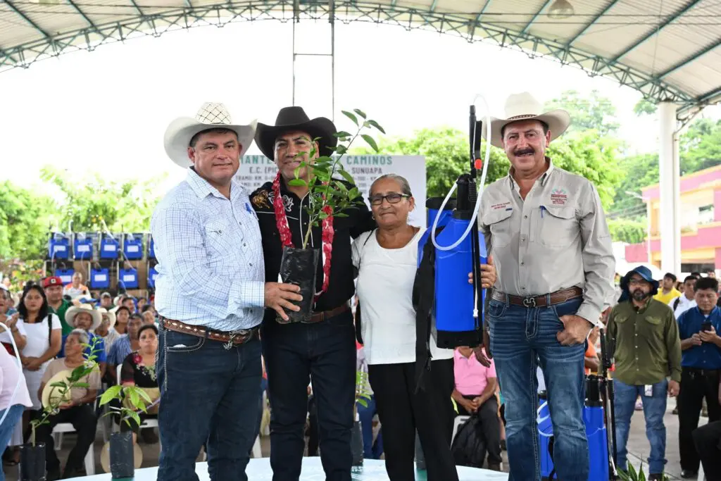 Four people holding seedlings and backpack sprayer