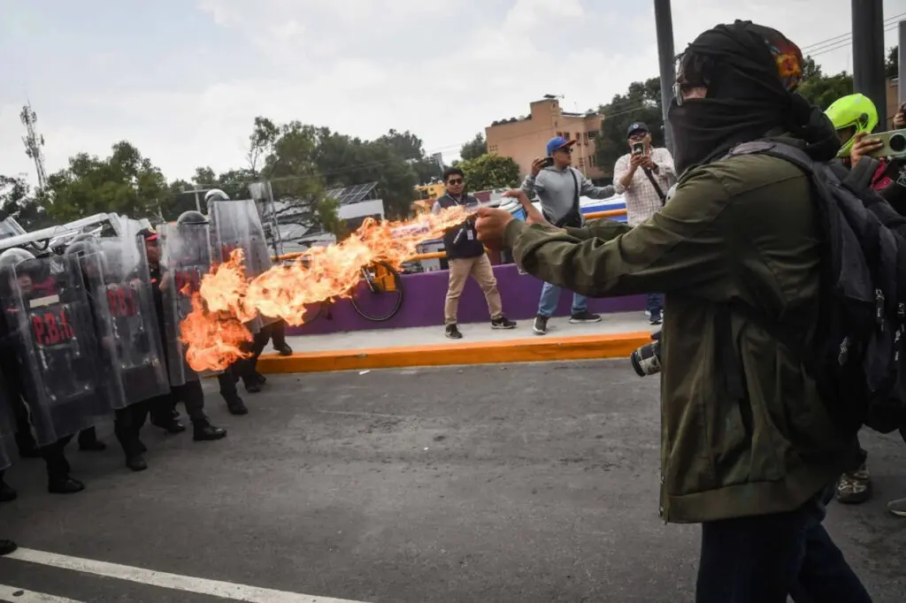 Masked protester spraying fire at riot police