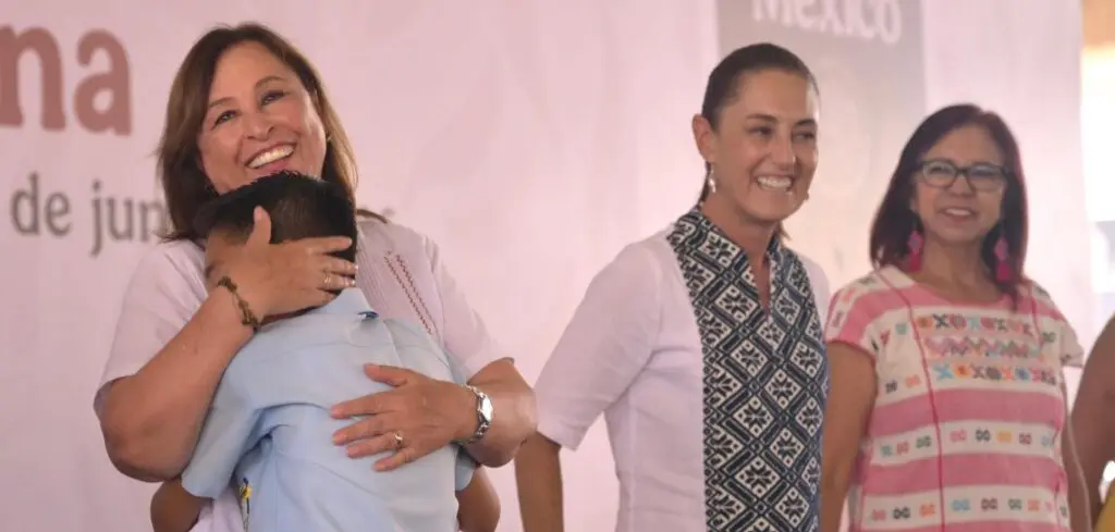 Women smiling at event, one hugging child