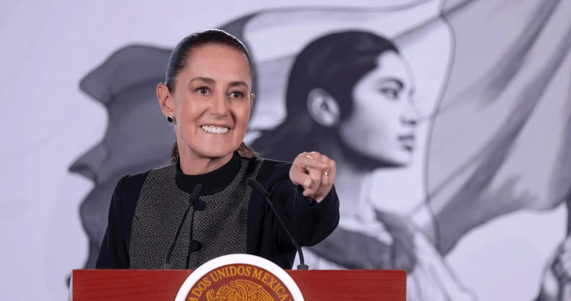 Smiling woman pointing while speaking at podium