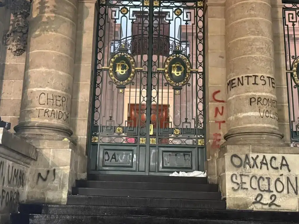 Graffiti-covered stone columns and ornate iron gates