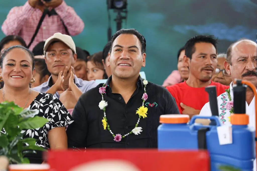 Smiling crowd at event, man wearing flower lei