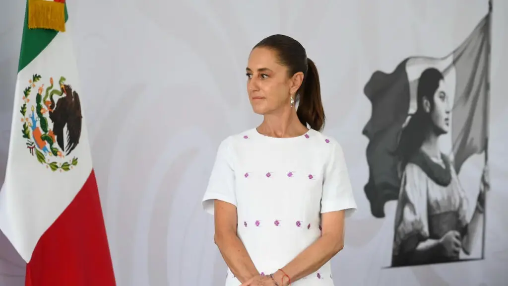 Woman beside Mexican flag and portrait mural