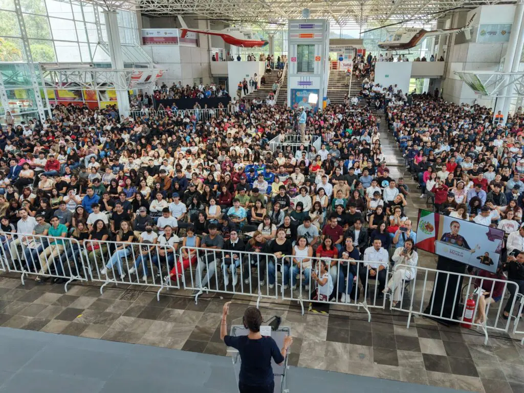 Speaker addressing large indoor audience at conference