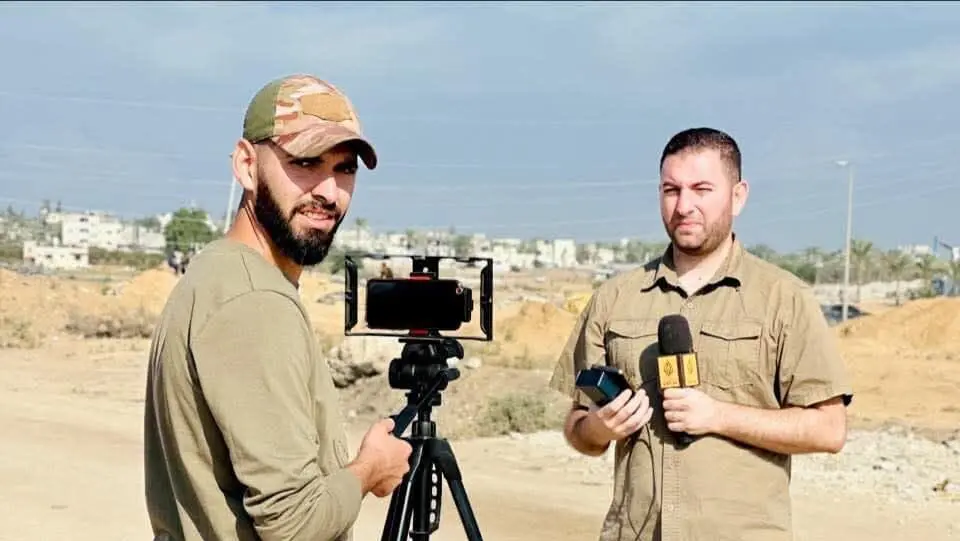 Two journalists filming outdoors near arid landscape