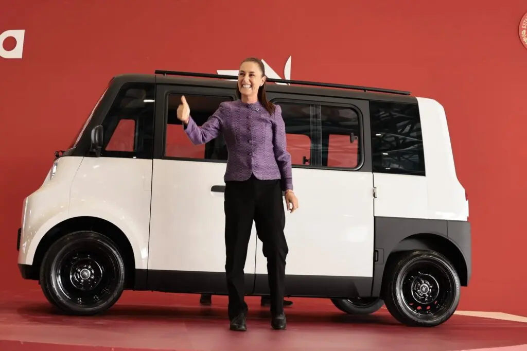Woman giving thumbs up beside compact white van