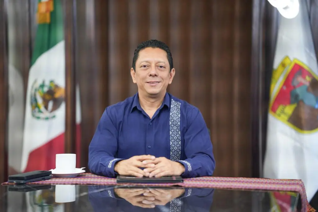 Smiling man seated at desk with Mexican flag