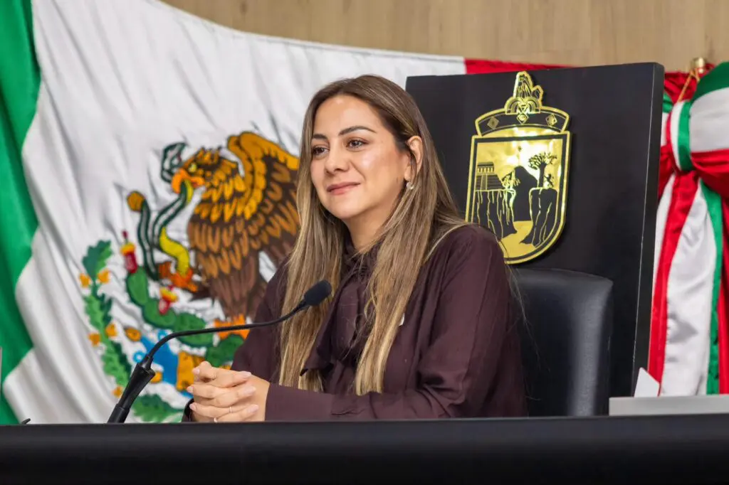 Woman seated at podium with Mexican flag