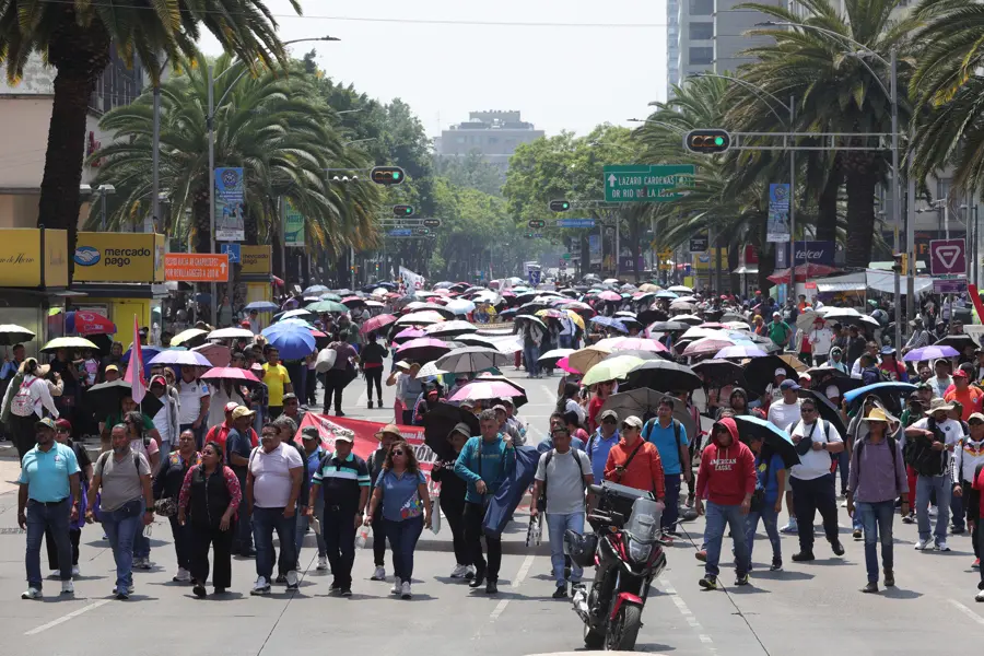 Crowd marching down city street with umbrellas