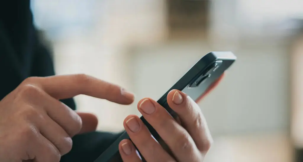 Joven consulta su teléfono celular tras el anuncio del nuevo calendario para vincular líneas móviles con la CURP en México.