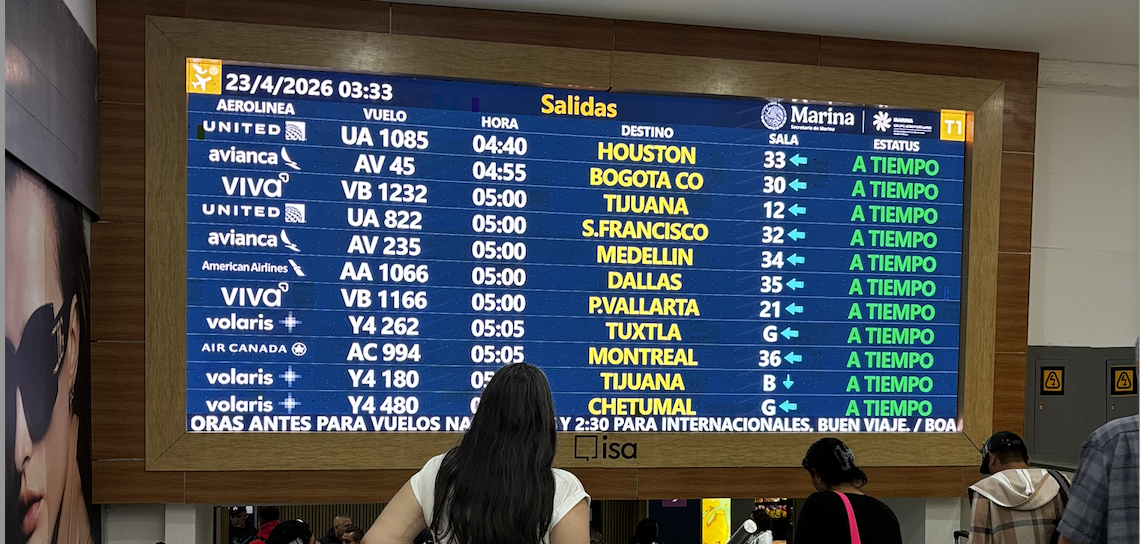 Large airport departures board above waiting passengers
