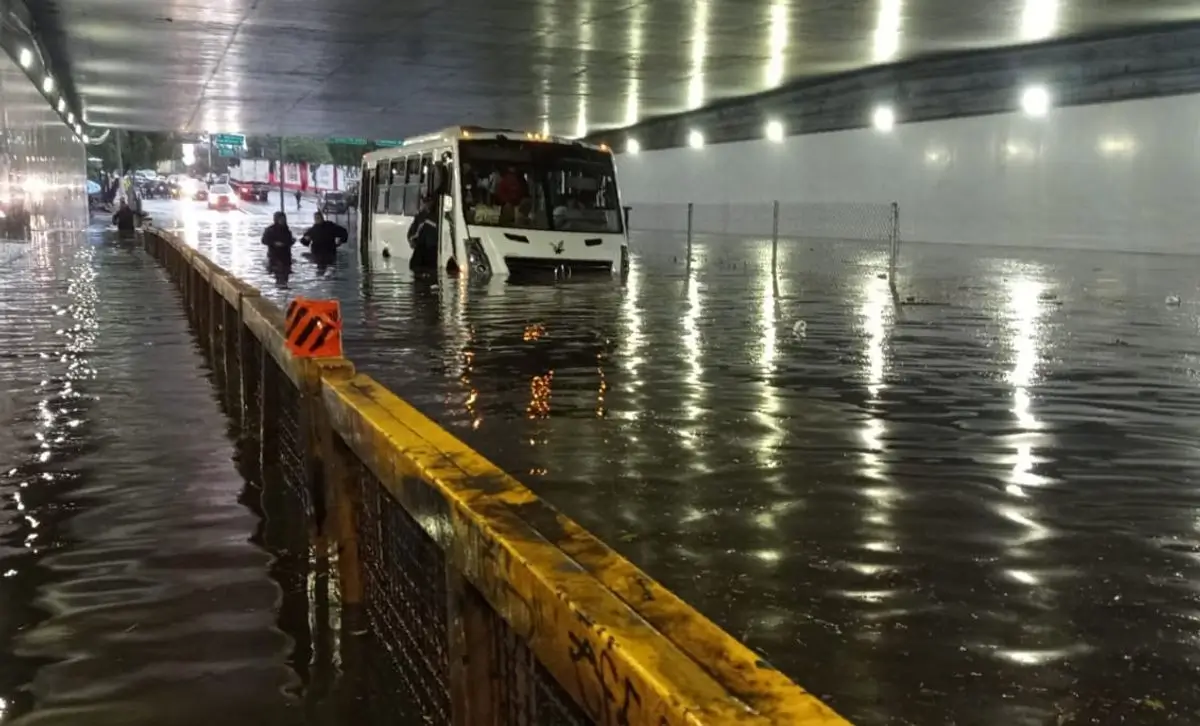 Microbús varado por inundación en paso a desnivel de la Ciudad de México