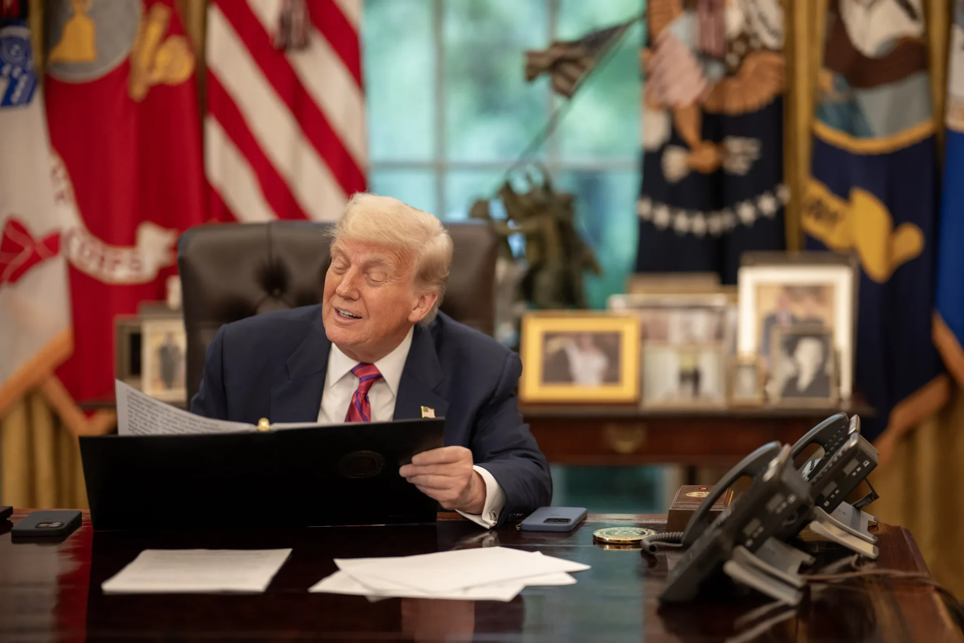 Smiling man at decorated desk with flags