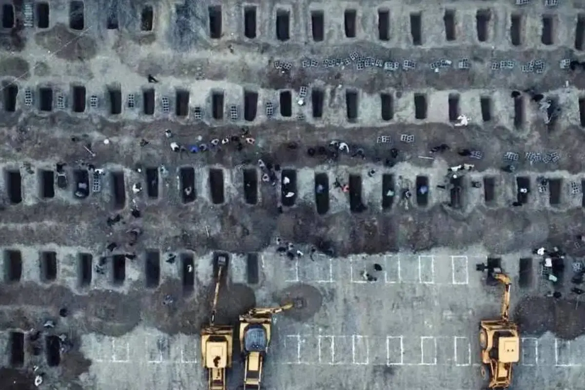 Vista aérea del funeral de niñas fallecidas tras un ataque a una escuela en Minab, Irán, donde familiares y excavadoras preparan decenas de tumbas en el cementerio.