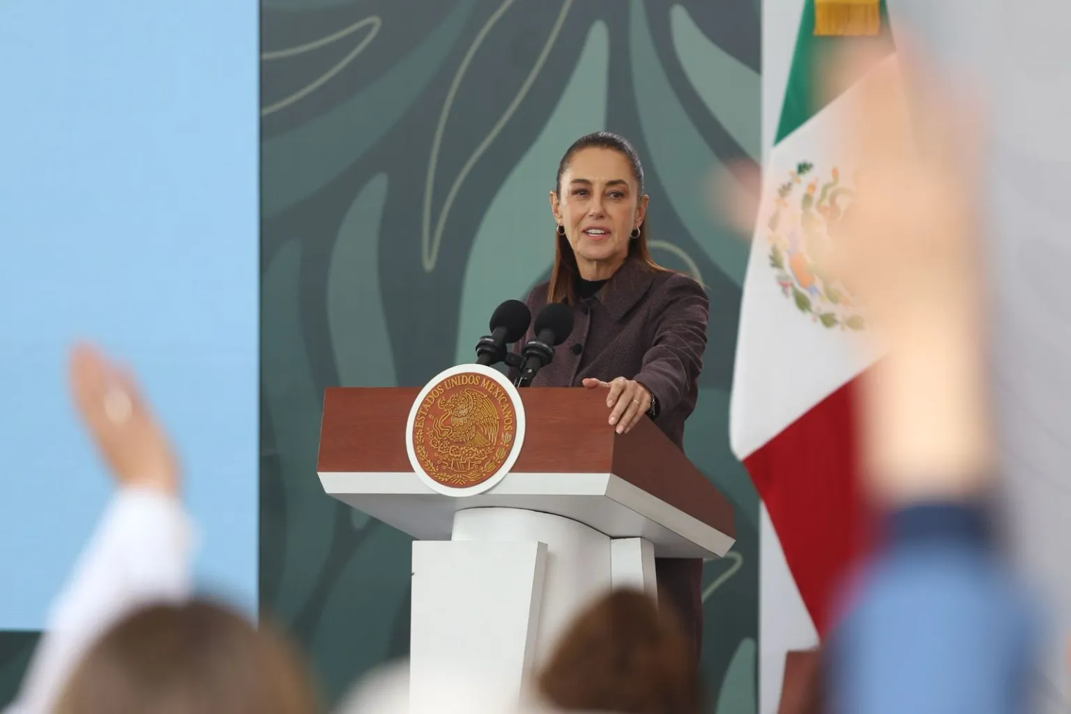Female speaker at podium with Mexican flag