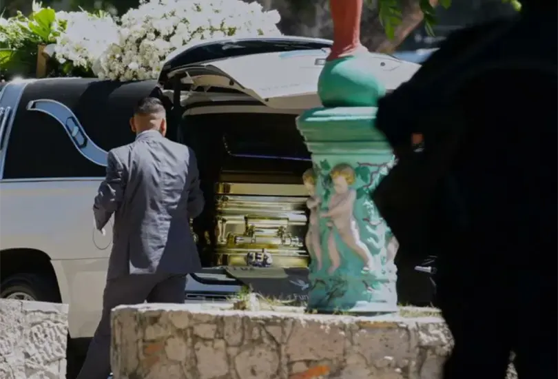 Ataud dorado cargado por personal de funeraria en Guadalajara.