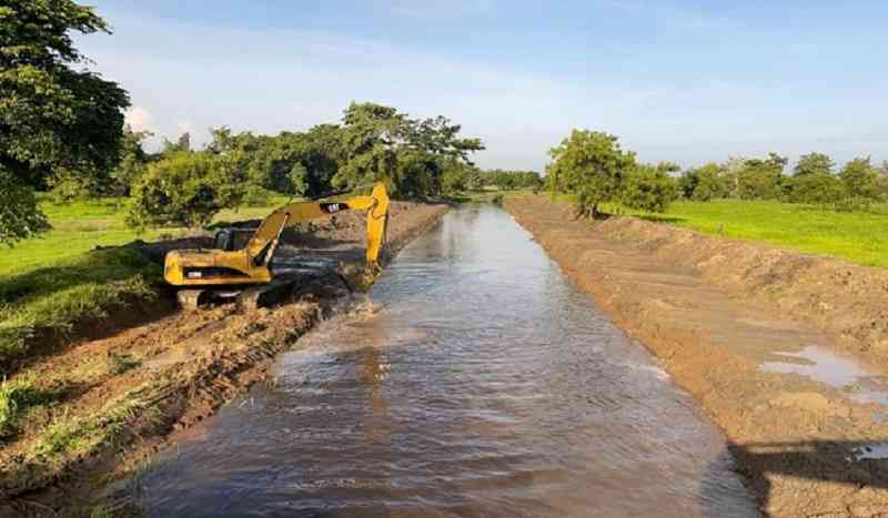 Yellow excavator digging irrigation canal
